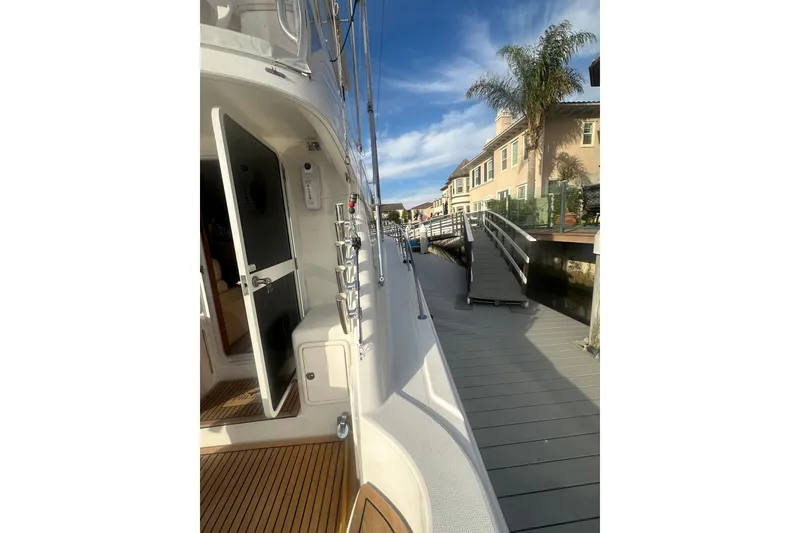 Slide: The Image of 2007 Riviera Sport Fisherman yacht docked beside waterfront homes under a clear blue sky. - 34