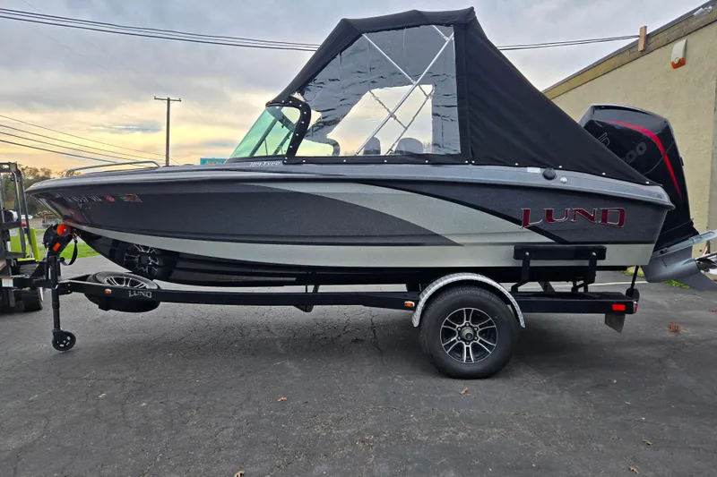 The Image of 2020 Lund 189 Tyee GL boat with black canopy on a trailer, parked outdoors. - 1