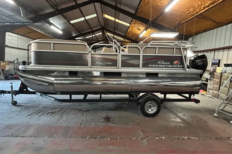 Slide: The Image of 2018 Sun Tracker Party Barge 18 DLX pontoon boat on trailer by a lake. - 2