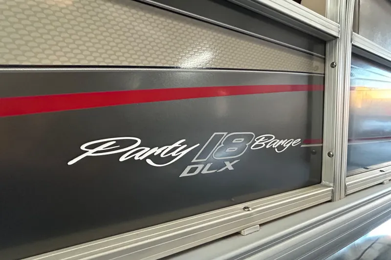 Slide: The Image of 2018 Sun Tracker Party Barge 18 DLX pontoon boat on trailer by the water. - 5
