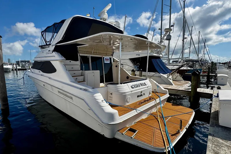 Slide: The Image of 1999 Sea Ray 440 Express Bridge yacht docked at marina under blue sky. - 1