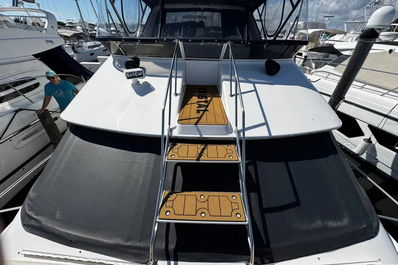 Slide: The Image of 1999 Sea Ray 440 Express Bridge yacht with sleek design and wooden steps. - 14