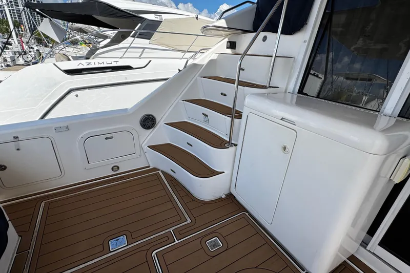 Slide: The Image of 1999 Sea Ray 440 Express Bridge yacht with teak deck and stairs, docked at marina. - 16