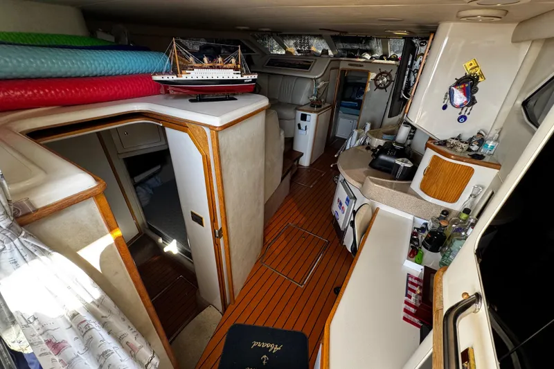 Slide: The Image of 1999 Sea Ray 440 Express Bridge interior with kitchenette, model ship, and wooden flooring. - 22