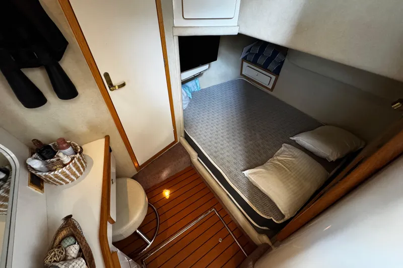Slide: The Image of 1999 Sea Ray 440 Express Bridge cabin interior with bed, pillows, and wooden flooring. - 26