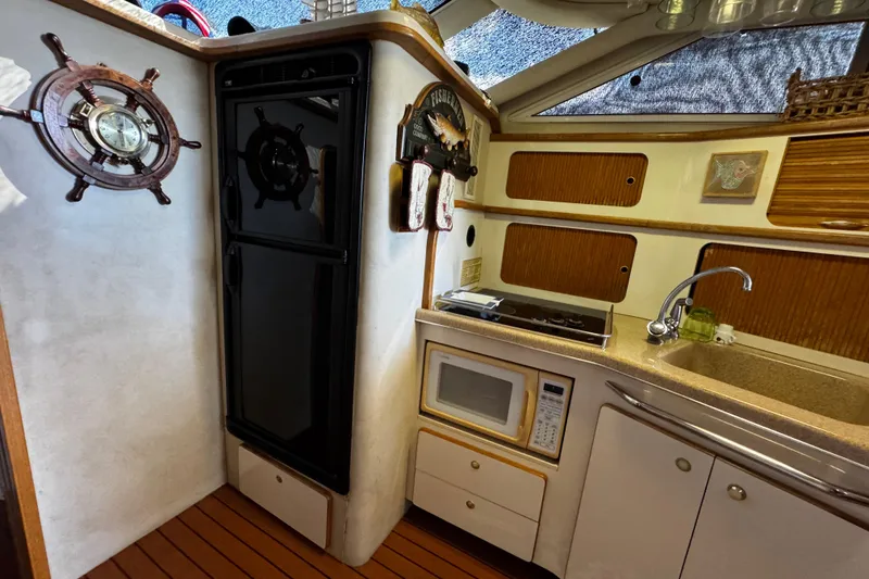 Slide: The Image of 1999 Sea Ray 440 Express Bridge kitchen with microwave, sink, and nautical decor. - 31