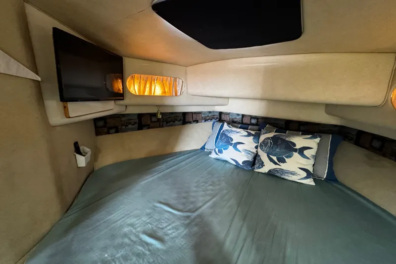 Slide: The Image of 1999 Sea Ray 440 Express Bridge cabin with bed, pillows, and wall-mounted TV. - 35