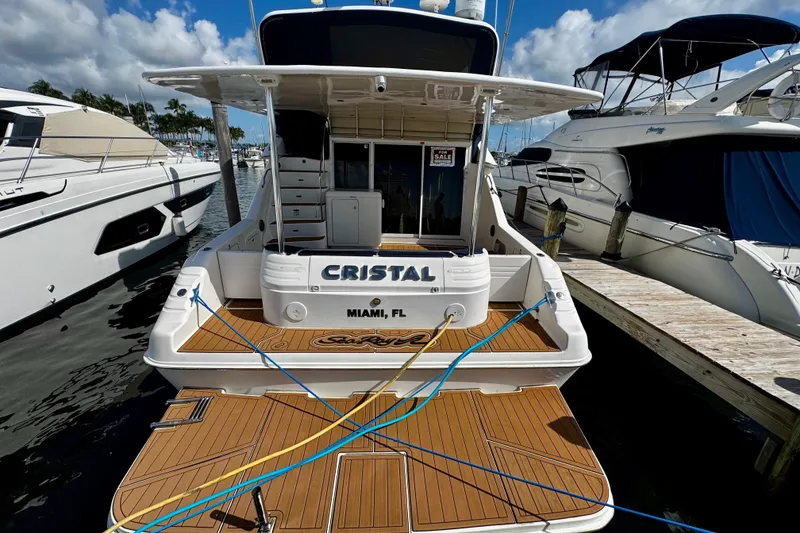 Slide: The Image of 1999 Sea Ray 440 Express Bridge yacht docked, featuring teak deck and "Cristal" nameplate. - 4