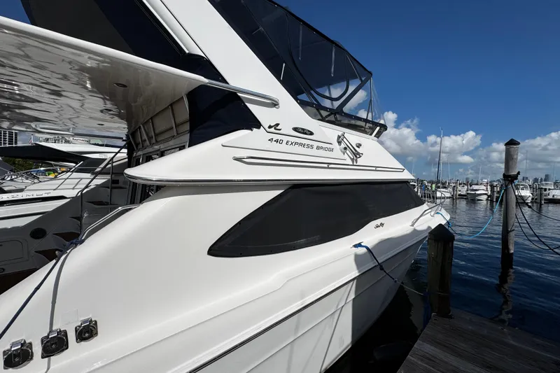 Slide: The Image of 1999 Sea Ray 440 Express Bridge yacht docked at marina under clear blue sky. - 6