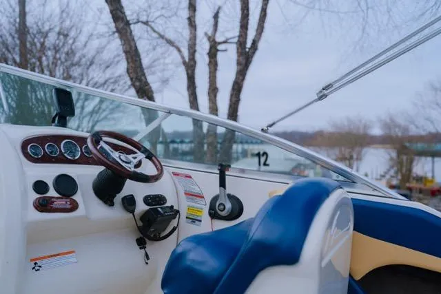 Slide: The Image of 2007 Sea Ray 215 Weekender boat interior with steering wheel and dashboard, near a lake. - 6