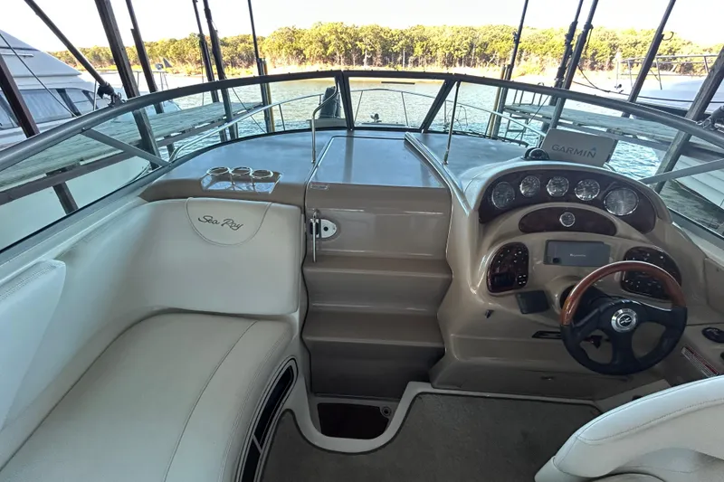 Slide: The Image of 2005 Sea Ray 280 Sundancer cockpit with steering wheel, gauges, and seating, overlooking water. - 12