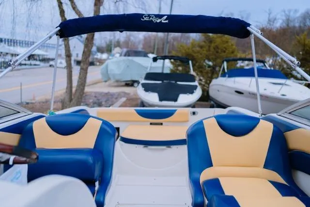 Slide: The Image of 2007 Sea Ray 215 Weekender boat interior with blue and beige seating, docked outdoors. - 9