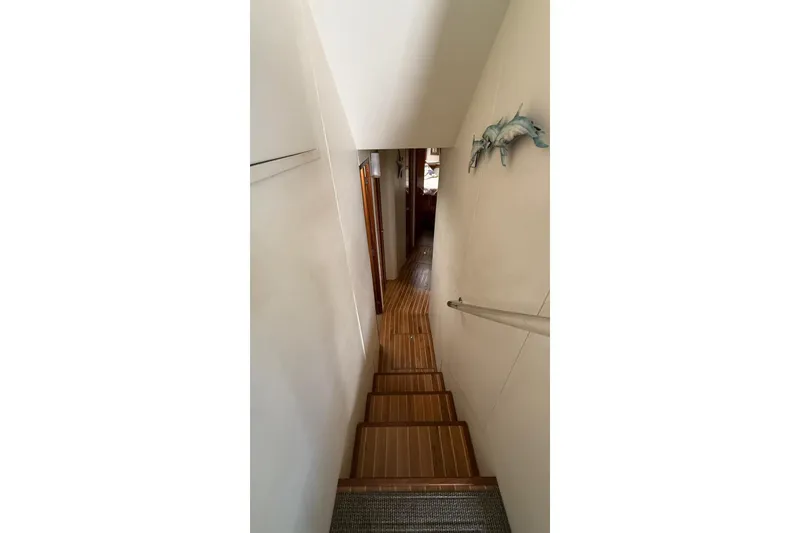 Slide: The Image of Stairway inside 1999 Viking 50 Convertible yacht with wooden flooring and wall decor. - 11