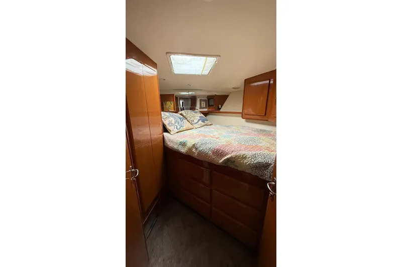 Slide: The Image of 1999 Viking 50 Convertible yacht bedroom with wood cabinets and colorful bedding. - 16