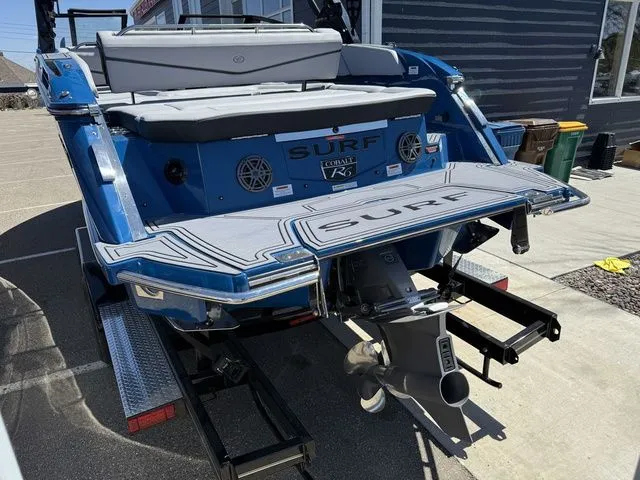 Slide: The Image of Rear view of a blue 2026 Cobalt R6 Surf boat on a trailer. - 5