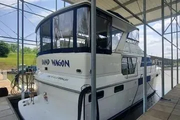 Slide: The Image of 1991 Carver 42 Aft Cabin Motor Yacht on tranquil water with lush greenery. - 5