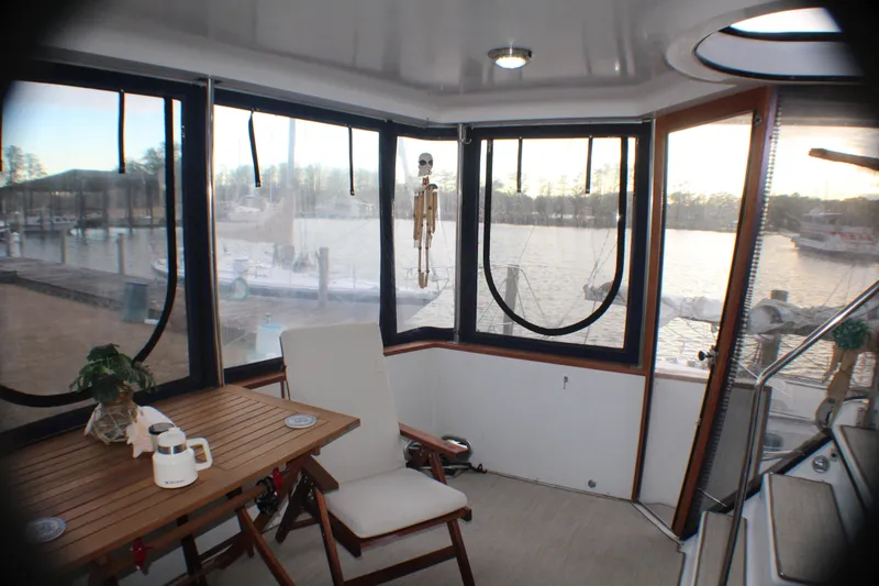 Slide: The Image of 1991 Carver 42 Aft Cabin Motor Yacht interior with wooden table and chair, marina view. - 31