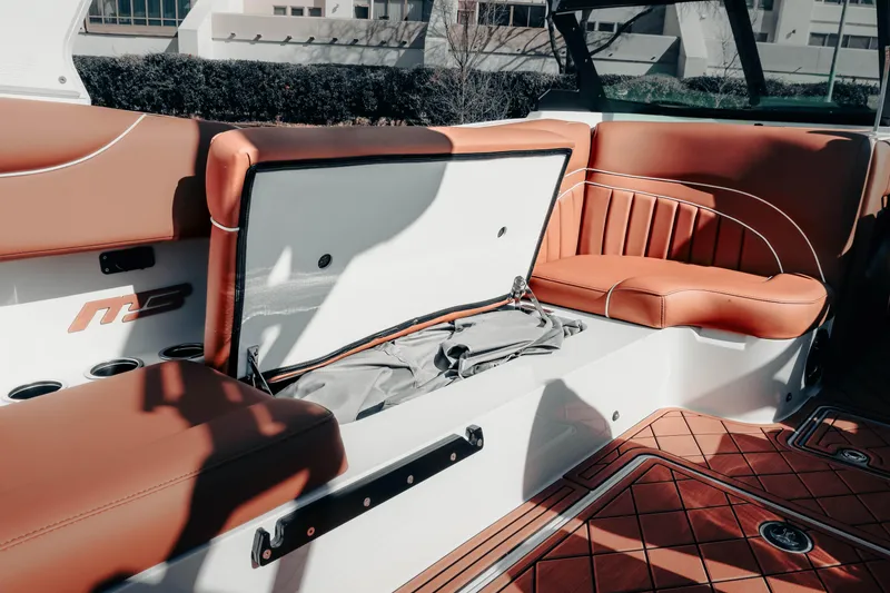 Slide: The Image of 2026 MB B52 23 Alpha boat interior with open storage compartment and brown seating. - 15