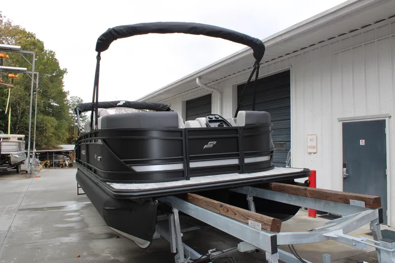 Slide: The Image of 2026 Starcraft SLS 3 Q DH pontoon boat on trailer, parked outside a warehouse. - 3