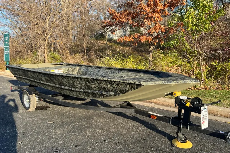 Slide: The Image of 2026 Tracker Grizzly 1648 Utility boat on trailer, parked outdoors in sunny setting. - 2