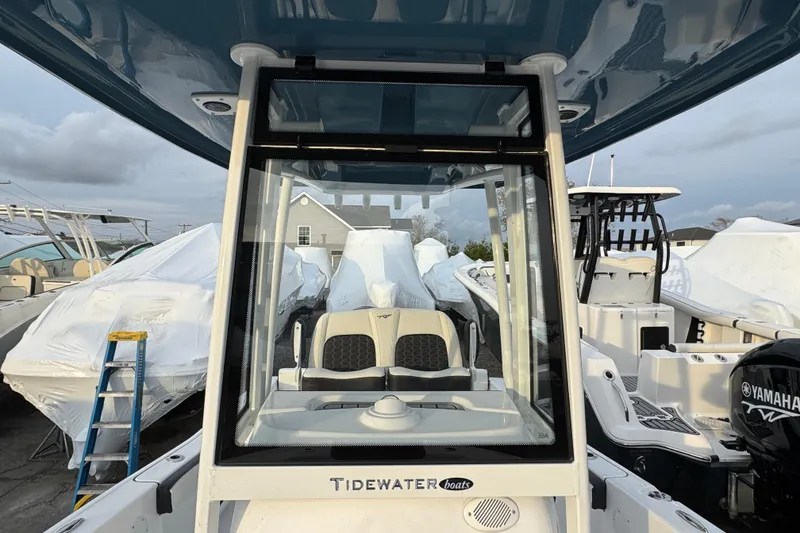 Slide: The Image of 2026 Tidewater 198 CC Adventure boat with Yamaha engine, docked among covered boats. - 12