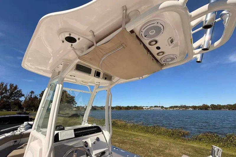 Slide: The Image of 2019 Everglades 243 Center Console boat interior with speakers and controls, near a scenic lake. - 13