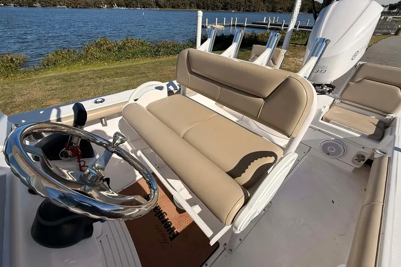 Slide: The Image of 2019 Everglades 243 Center Console boat with beige seating and chrome steering wheel by the water. - 8