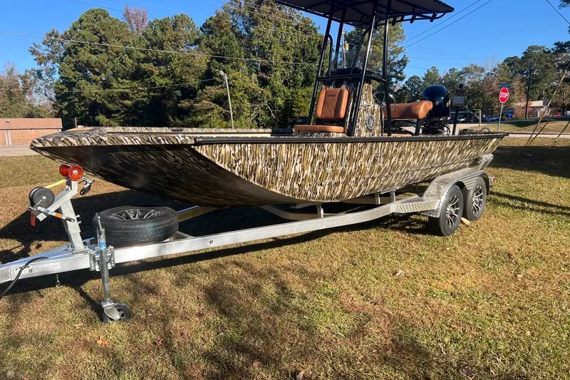 The Image of 2026 Avid 20 ROGUE CC boat on trailer, camouflage design, parked on grass. - 0