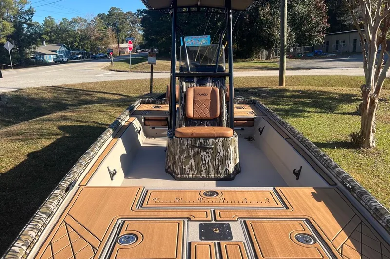 Slide: The Image of 2026 Avid 20 ROGUE CC boat with camo seating and wood accents, parked outdoors. - 3