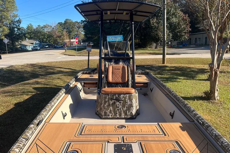 Slide: The Image of 2026 Avid 20 ROGUE CC boat with camo seating and wood accents, parked outdoors. - 5