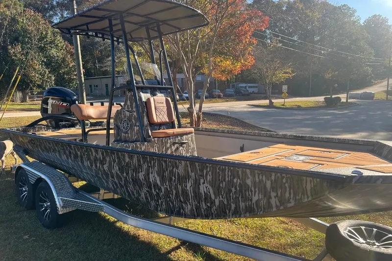 Slide: The Image of 2026 Avid 20 ROGUE CC boat on trailer, camo design, parked outdoors. - 6