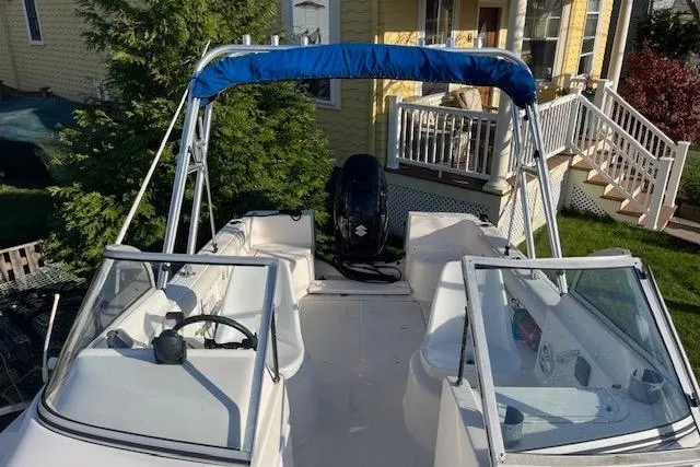 Slide: The Image of 2003 Palm Beach 22 Dual Console boat with blue canopy, parked near a house. - 5