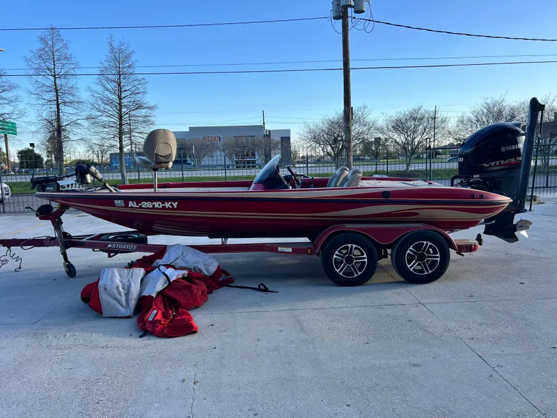 Slide: The Image of 2004 Stratos 201 Pro XL boat on trailer, parked outdoors with gear nearby. - 5