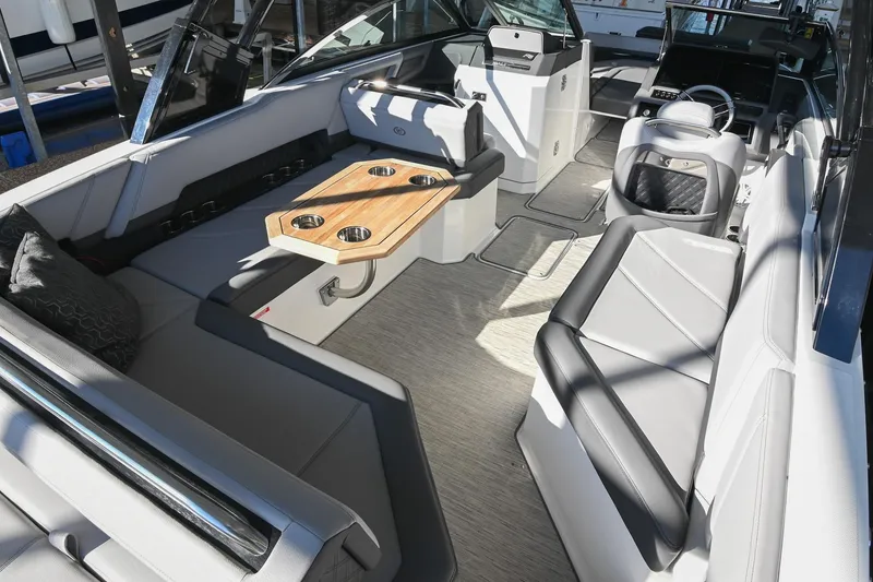 Slide: The Image of 2024 Cobalt R8 boat interior with luxurious seating and wooden table in marina setting. - 13