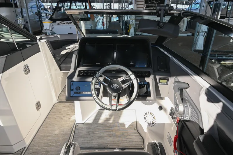 Slide: The Image of 2024 Cobalt R8 boat interior with modern steering and seating in a marina setting. - 29