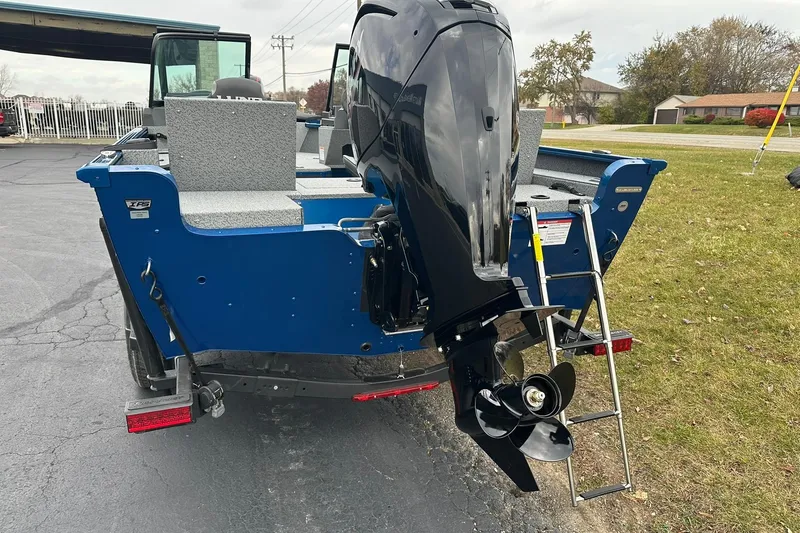Slide: The Image of 2026 Lund 1675 Adventure Sport boat with outboard motor and ladder, parked on pavement. - 3