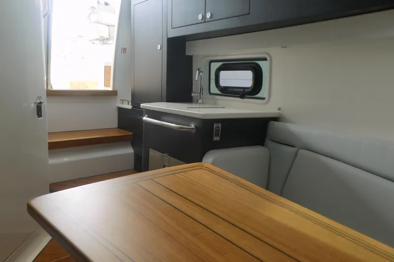 Slide: The Image of Interior of 2026 Boston Whaler 380 Realm, featuring a compact kitchen and seating area. - 17