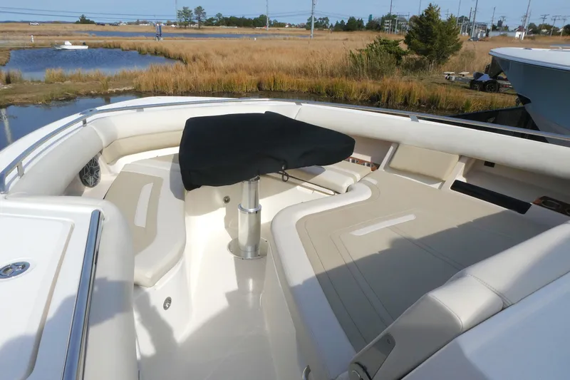 Slide: The Image of 2026 Boston Whaler 380 Realm boat interior with cushioned seating and table, near water. - 18