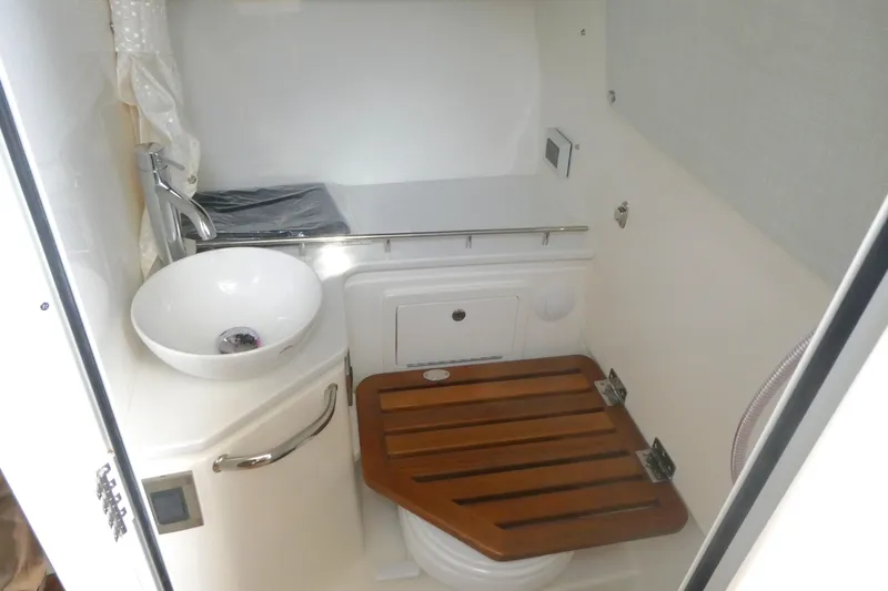 Slide: The Image of 2026 Boston Whaler 380 Realm boat bathroom with sink and wooden seat. - 21
