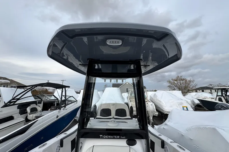 Slide: The Image of 2026 Tidewater 220 LXF boat with T-top, surrounded by other boats in storage. - 14