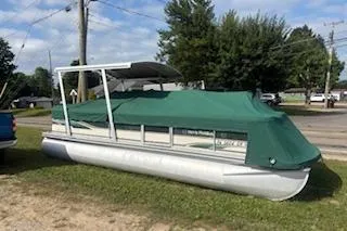 The Image of 2001 Harris-Kayot Classic 240 O/B pontoon boat with green cover, parked on grass. - 0