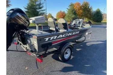 Slide: The Image of 2018 Tracker Super Guide V-16 SC boat with Mercury engine, parked outdoors on a sunny day. - 2