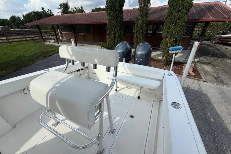 Slide: The Image of 2008 Contender 23 Open boat with dual engines and white seating, parked near a wooden building. - 12
