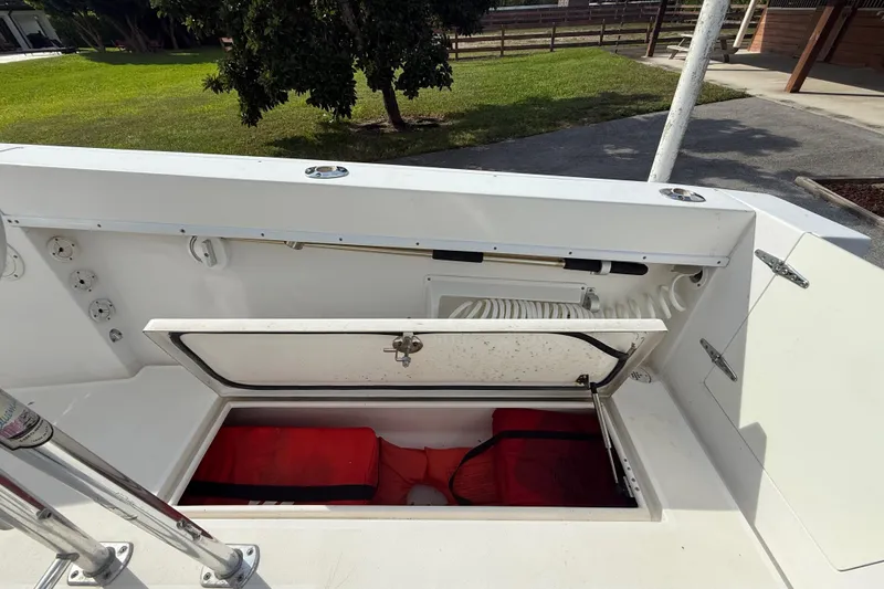 Slide: The Image of 2008 Contender 23 Open boat storage compartment with red life jackets, outdoor setting. - 15