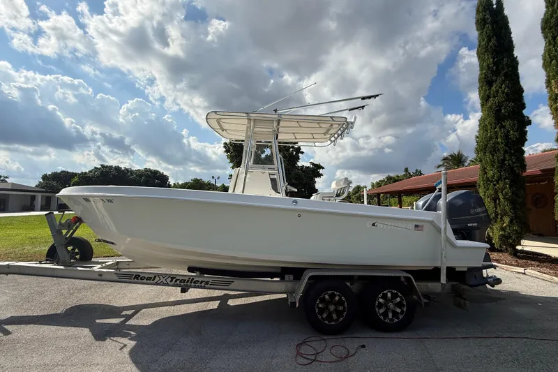 The Image of 2008 Contender 23 Open boat on trailer under cloudy sky. - 2