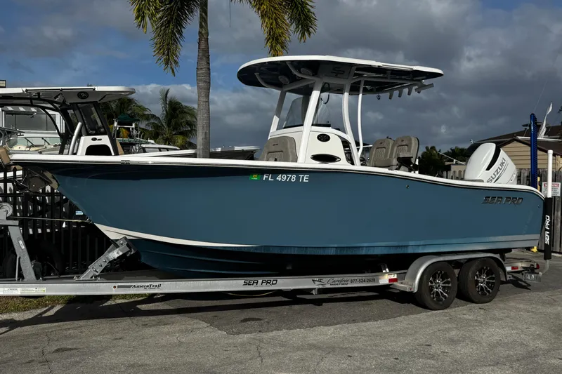 Slide: The Image of 2022 Sea Pro 239 Center Console boat on trailer, parked near palm trees. - 2