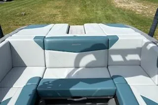 Slide: The Image of 2025 MasterCraft NXT22 boat interior with teal and white seating, grassy background. - 3