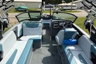 Slide: The Image of 2025 MasterCraft NXT22 boat interior with seating and steering wheel, docked outdoors. - 8