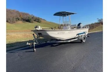 Slide: The Image of 2006 Carolina Skiff 198 DLX boat on trailer, parked on asphalt near grassy hills. - 0
