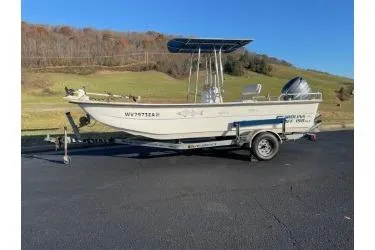 Slide: The Image of 2006 Carolina Skiff 198 DLX boat on trailer, parked on asphalt with scenic background. - 1